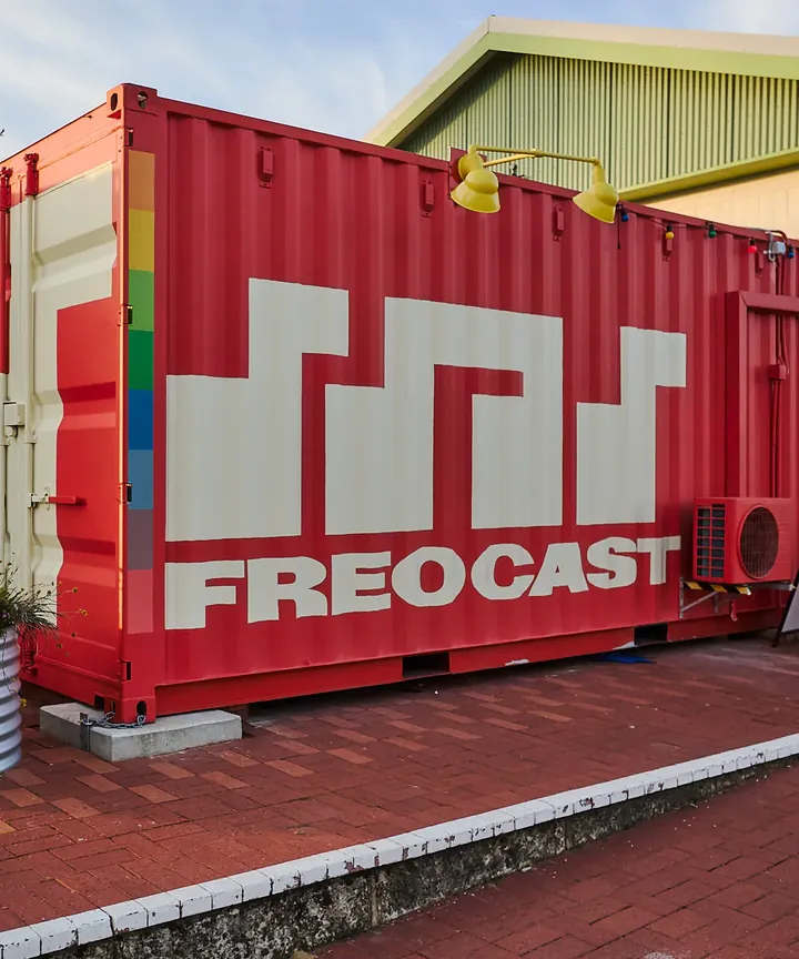 White FREOCAST identity painted across the red container radio studio